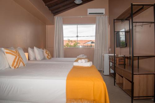 a bedroom with a large white bed with a window at Porteño Loft Búzios in Búzios