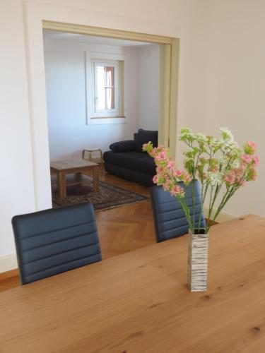 a living room with two chairs and a table with flowers at Chez Carole (4 pièces) in Neuchâtel