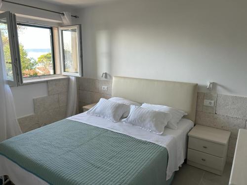 Schlafzimmer mit einem Bett mit weißer Bettwäsche und Kissen in der Unterkunft Apartment Esperansa in Brela