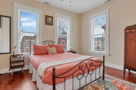 - une chambre dotée d'un lit avec des draps orange et des fenêtres dans l'établissement Historic Elegance Retreat - Columbus Downtown, à Columbus