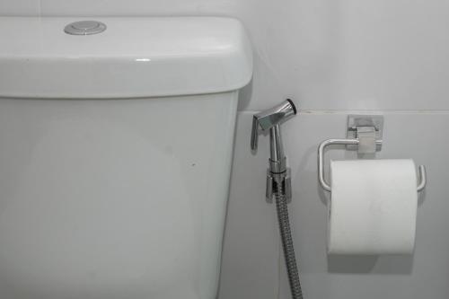 a toilet with a hose hooked up to a roll of toilet paper at Porteño Loft Búzios in Búzios