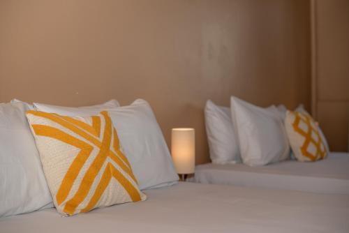 a bedroom with two beds with pillows and a candle at Porteño Loft Búzios in Búzios
