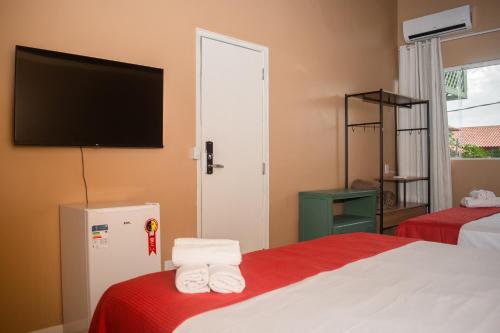 a hotel room with two beds and a flat screen tv at Porteño Loft Búzios in Búzios