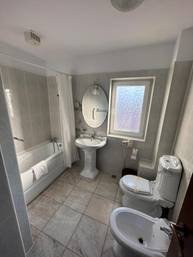 La salle de bains est pourvue d'un lavabo, d'une baignoire et de toilettes. dans l'établissement Hotel Bliss, à Bucarest
