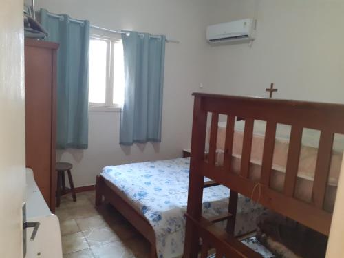 een slaapkamer met een bed met blauwe gordijnen en een kruis bij Casa com boas acomodações in Itanhaém