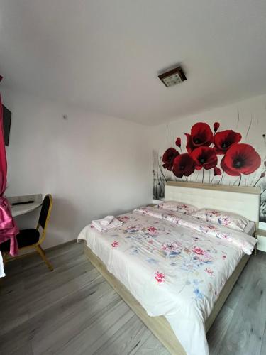 a bedroom with a bed with red flowers on the wall at Sunset Expanse in Turda