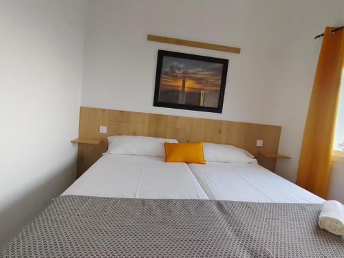 a bedroom with a bed with an orange pillow on it at Hierro in Frontera