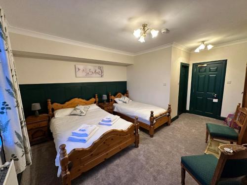 Herrislea House Hotel في Tingwall: غرفة نوم بسريرين وكرسي