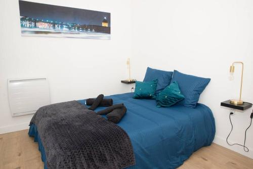 - un lit bleu dans une chambre blanche avec des oreillers bleus dans l'établissement Superbe T2 au coeur de Lalande+Parking privé, à Toulouse