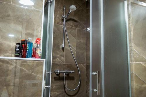 a shower with a shower head in a bathroom at White Apartment Prishtina in Pristina