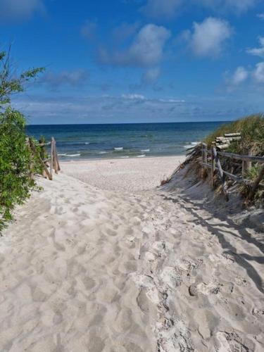 a sandy beach with a fence and the ocean at Pod Cisem in Kierzkowo