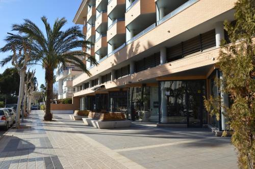 a building with palm trees in front of a sidewalk at Albir Beach Apt in Albir