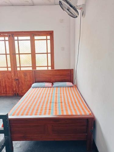 a wooden bed in a room with a window at Puraya'S Lodge in Anuradhapura