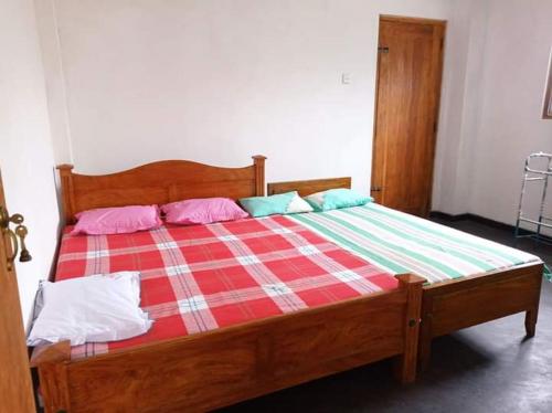 drewniane łóżko z różowymi i niebieskimi poduszkami w obiekcie Puraya'S Lodge w mieście Anuradhapura