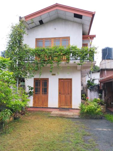 Casa blanca con puertas de madera y patio en Puraya'S Lodge, en Anuradhapura