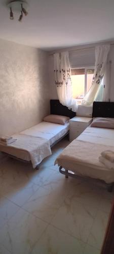 um quarto com três camas e uma janela em Apartamento vacaciones em Palafrugell