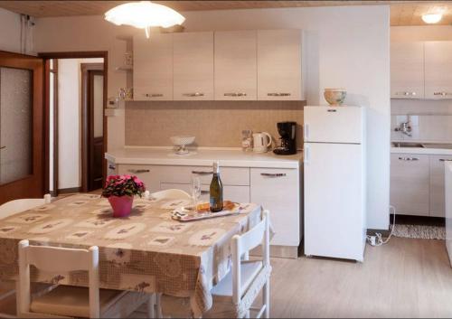 a kitchen with a table and a white refrigerator at Casa Vacanza al mulino in Cremia