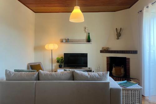 a living room with a white couch and a television at Casa dos Frades in Vinhais