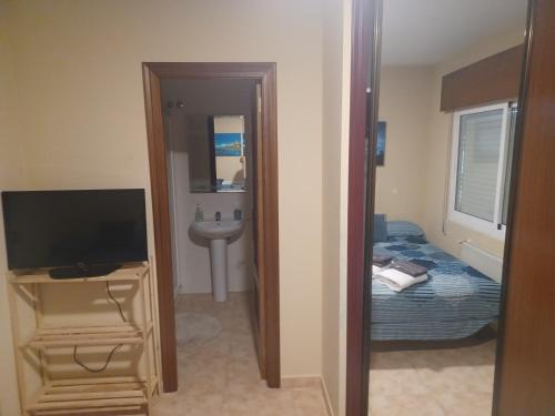 1 dormitorio con cama, TV y lavabo en Alojamientos O Camiño, en A Coruña
