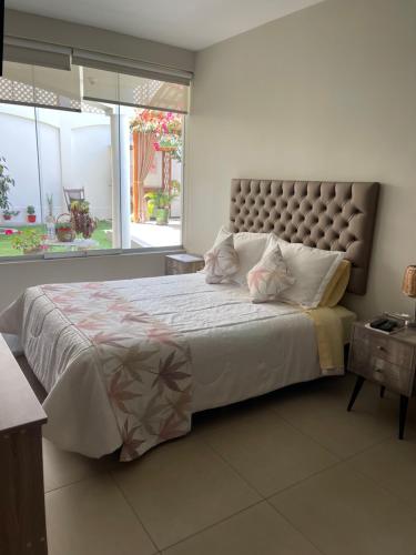 a bedroom with a large bed with a large window at Apart-hotel Villakayro in Moquegua