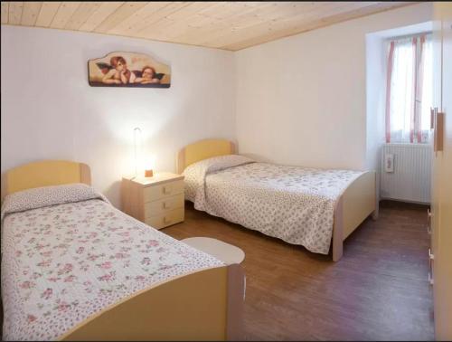 a bedroom with two beds and a picture on the wall at Casa Vacanza al mulino in Cremia