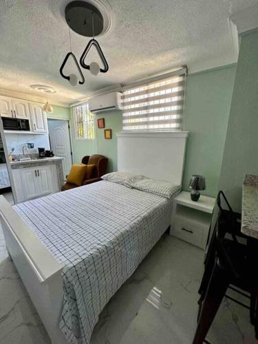 um quarto com uma cama branca e uma cozinha em Apartaestudio Doña Rosa em San Pedro de Macorís
