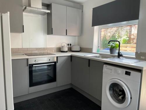 a white kitchen with a washing machine and a sink at 4@No.4. A cosy spot for 4 and one furry friend in Cawood