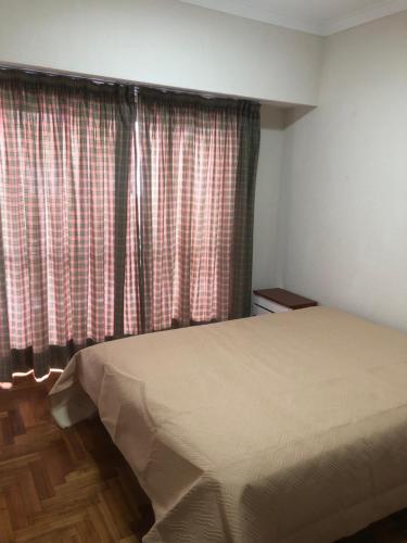 1 dormitorio con 1 cama y una ventana con cortinas en Mar del plata en Mar del Plata
