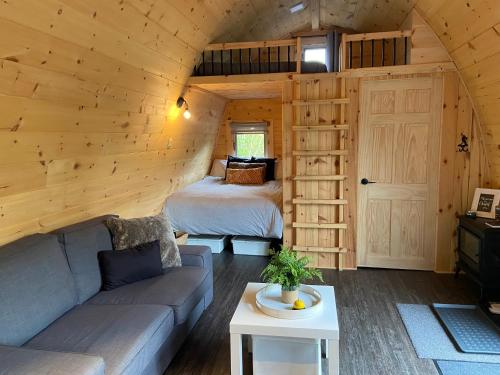 a living room with a bed and a couch in a cabin at Le POD'Stress / Nature et tranquilité in Saint-Alexis-des-Monts