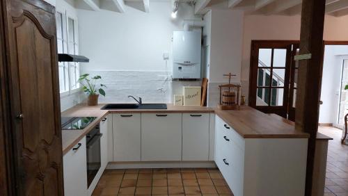 une cuisine avec des armoires blanches et un évier dans l'établissement Maison La Rivière, à Reffuveille