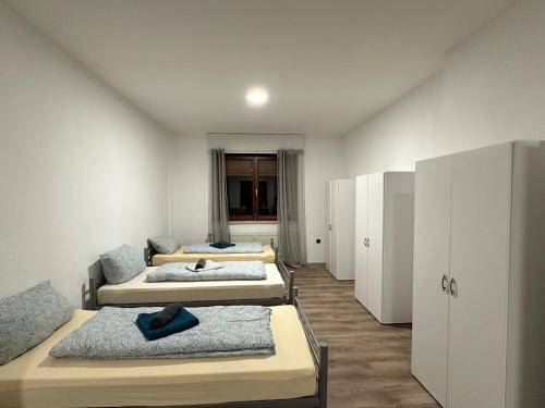 four beds in a room with white walls and cabinets at Duisburg FeelHome, Flughafen nah, 6 Personen, Badewanne, Zentral, WiFi, Ground Floor in Duisburg
