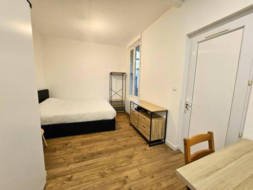 een slaapkamer met een bed, een dressoir en een tafel bij NERO studio confort tt équipé! in Villejuif