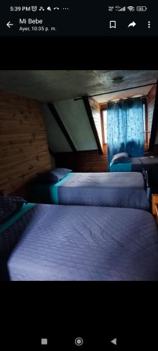 two beds in a room with blue curtains at Hostal NF rocket in Los Ángeles