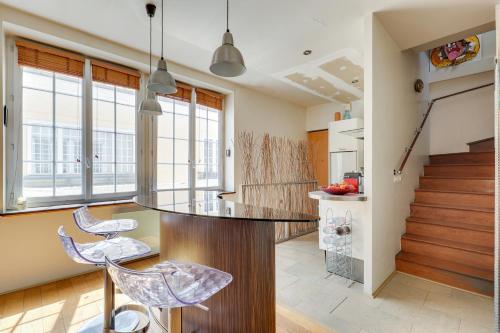 - une cuisine avec un bar avec des tabourets et des fenêtres dans l'établissement Duplex calme et lumineux au cœur de Bastille, à Paris