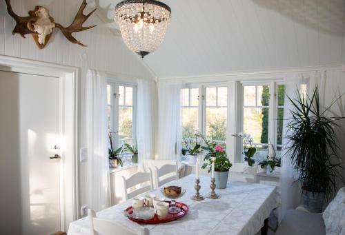 a white dining room with a table and a chandelier at Grandma's cottage in Tanum