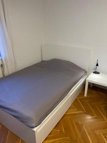 uma cama branca num quarto com uma mesa lateral em Apt. 80 m2, wifi, jacuzzi, 5 guests, 10min center em Zagreb