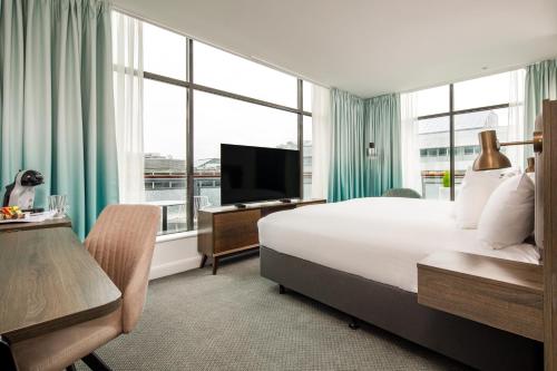 ミルトン・キーンズにあるホリデイ イン ミルトン ケインズ セントラルの大型ベッドとテレビが備わるホテルルームです。