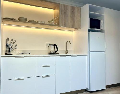 a kitchen with white cabinets and a refrigerator at The Saasveld in Cape Town