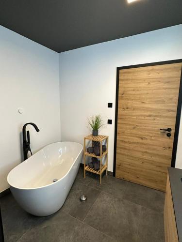 a large white tub in a bathroom with a wooden door at woidpanorama Ferienwohnungen in Neuschönau
