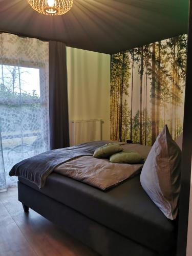 a bed with green pillows in a bedroom with a window at woidpanorama Ferienwohnungen in Neuschönau