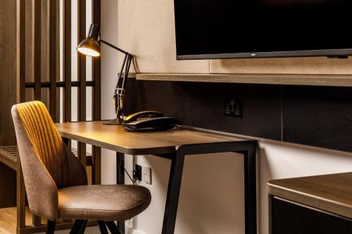 a desk with a lamp and a chair in a room at Holiday Inn Milton Keynes Central by IHG in Milton Keynes
