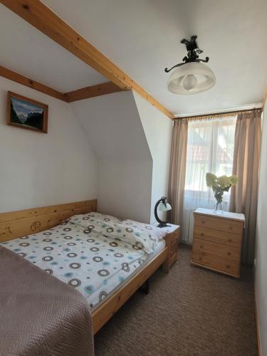 a bedroom with a bed and a dresser and a window at Willa Świerk - Panorama Tatr in Zakopane