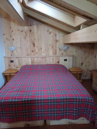 ein Schlafzimmer mit einem Bett in einem Zimmer mit Holzwänden in der Unterkunft Chalet Shalom in Livigno