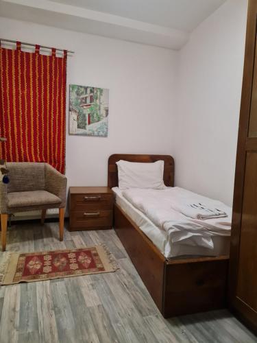 a bedroom with a bed and a chair and a window at Guesthouse Hotel My Home in Prizren