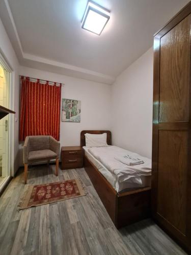 a bedroom with a bed and a chair and a window at Guesthouse Hotel My Home in Prizren