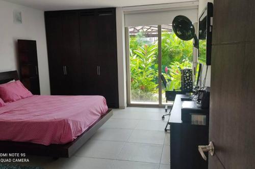 um quarto com uma cama com lençóis cor-de-rosa e uma janela em Casa de campo Villavicencio em Villavicencio