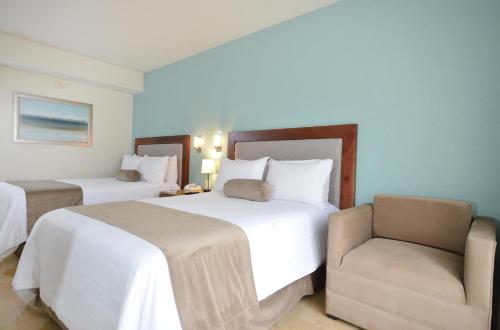 a hotel room with two beds and a chair at HB Xalapa in Xalapa