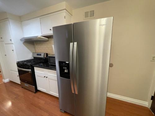 a stainless steel refrigerator in a kitchen with white cabinets at Tao house in La Verne