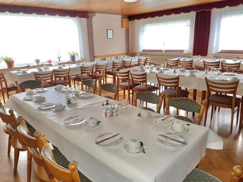 una sala da pranzo con tavoli e sedie bianchi e finestre di Gasthof Rhönlust a Bischofsheim an der Rhön