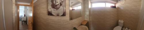 une salle de bains avec une peinture d'une femme sur le mur dans l'établissement Habitaciones en Casa compartida Retamar, à Almería